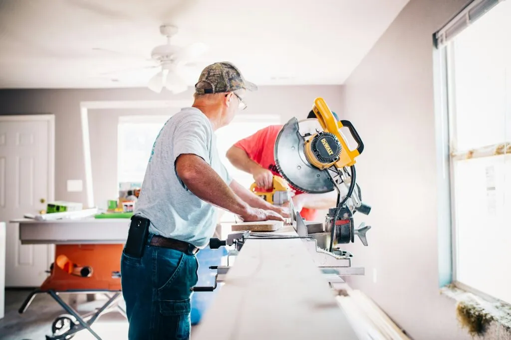 Carpenters measuring and cutting trim with a miter saw