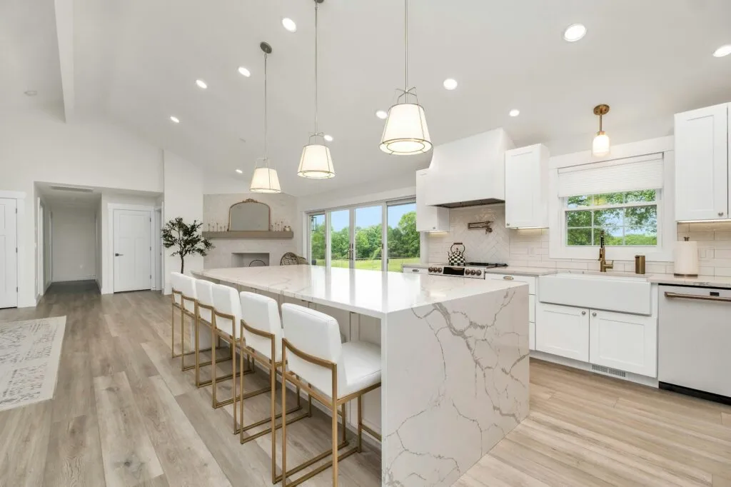 Bright kitchen with marble waterfall island and pendant lights